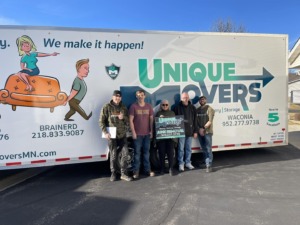 Unique Mover team and homeowners standing in front of a UM trailer