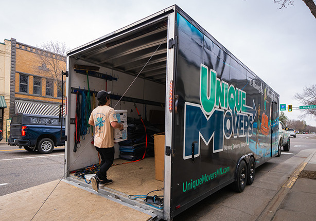 Unique Movers team member loading boxes into a trailer